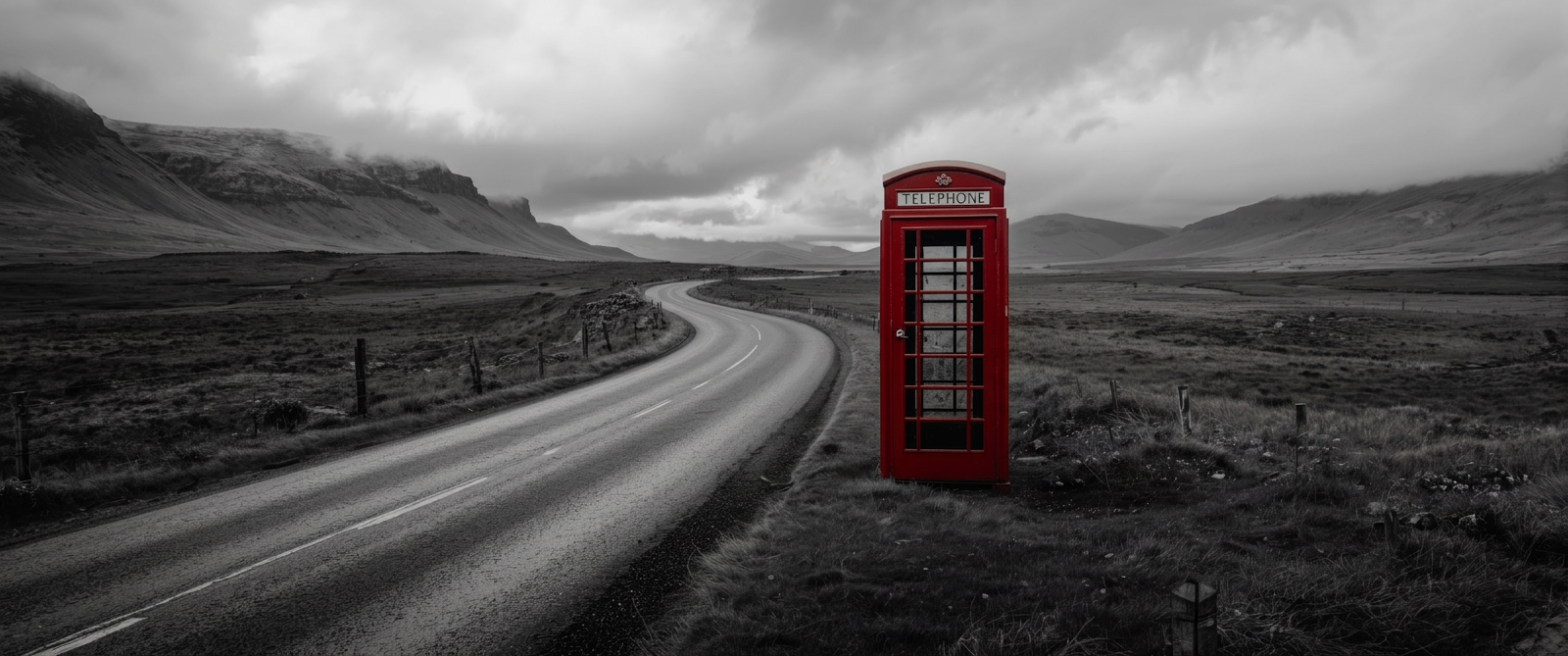 Red telephone box beside a winding empty road through Scottish Highland moorland